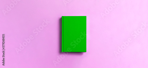 green book on pink background. ピンク背景の上の緑色の本