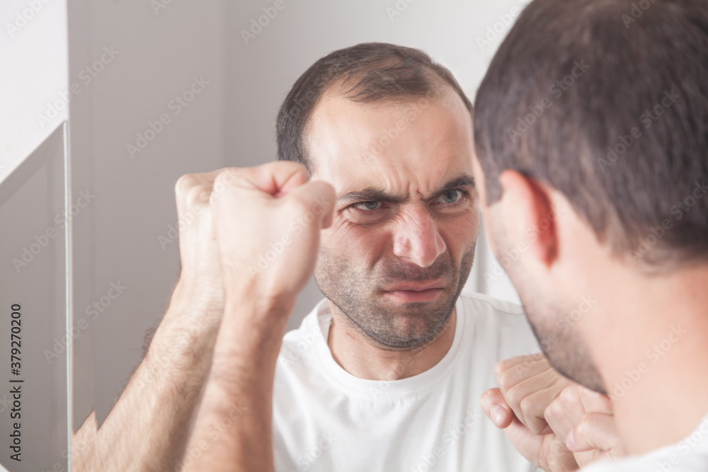 Obraz premium Caucasian angry man looking in mirror.