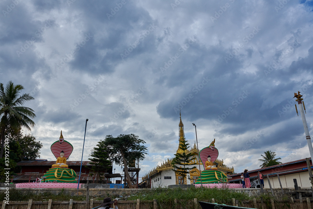 Naklejka premium Inle Lake is in the Shan Hills of Myanmar. At its southwestern edge, Phaung Daw Oo Paya is a tiered pagoda with gilded Buddha statues. In the hills, near the market town of Indein, the stupas of Shwe 