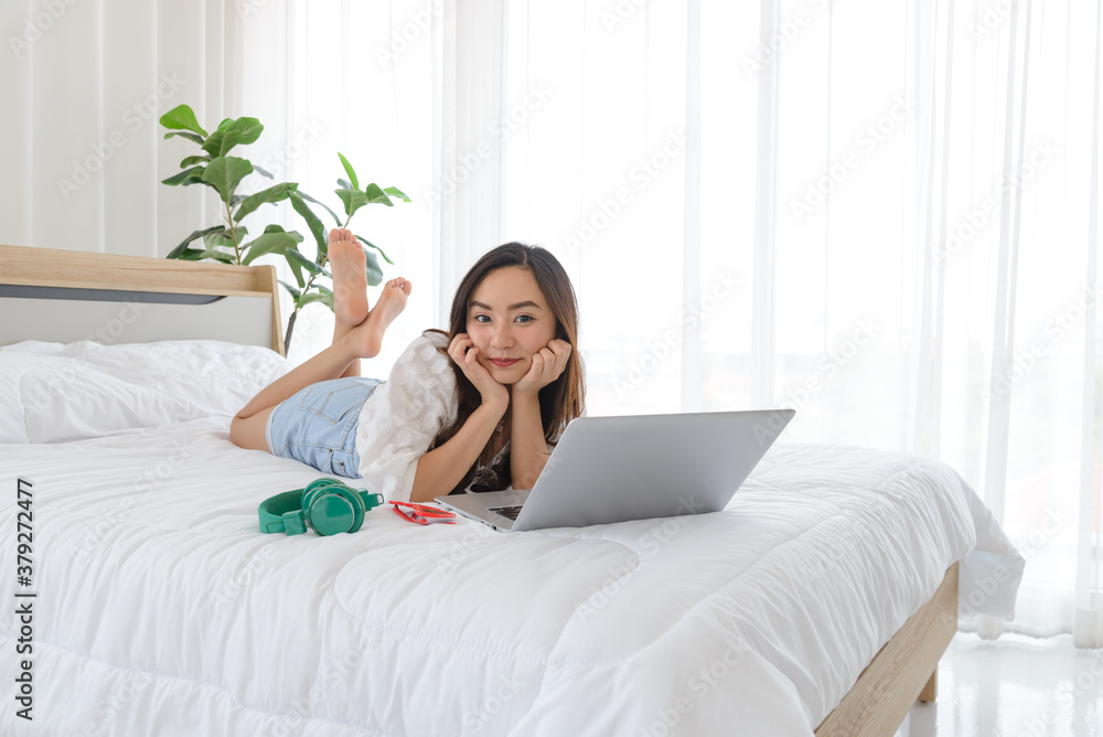 Beautiful young Asian woman relaxing and using a lapto on her bed. Beautiful young Asian woman relaxing and using a lapto on her bed.