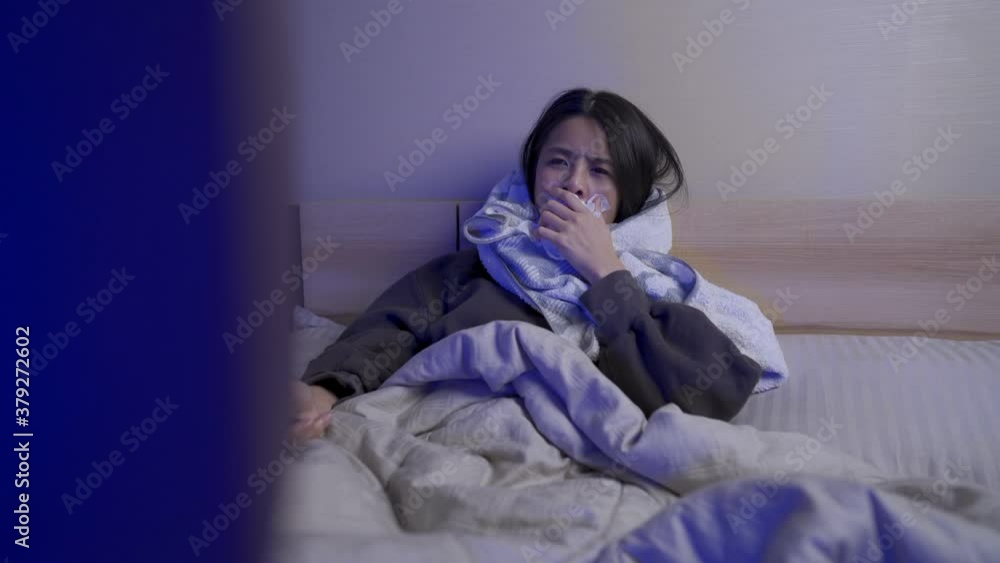 Asian young woman cough lying down inside blanket on the bed watching