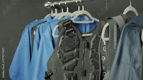 A figure removes a body armour vest from a clothes rack. photo