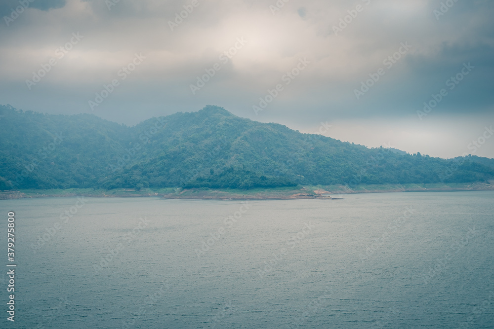 Obraz premium Scenic mountain range next to deep river shrouded in mist landscape view at Thailand.