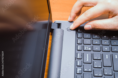 Finger pushing start power button on the laptop computer. Press turn off shutdown keyboard on notebook hardware equipment. Above view with copy space. Technology ban and stop. Social disconnect tablet