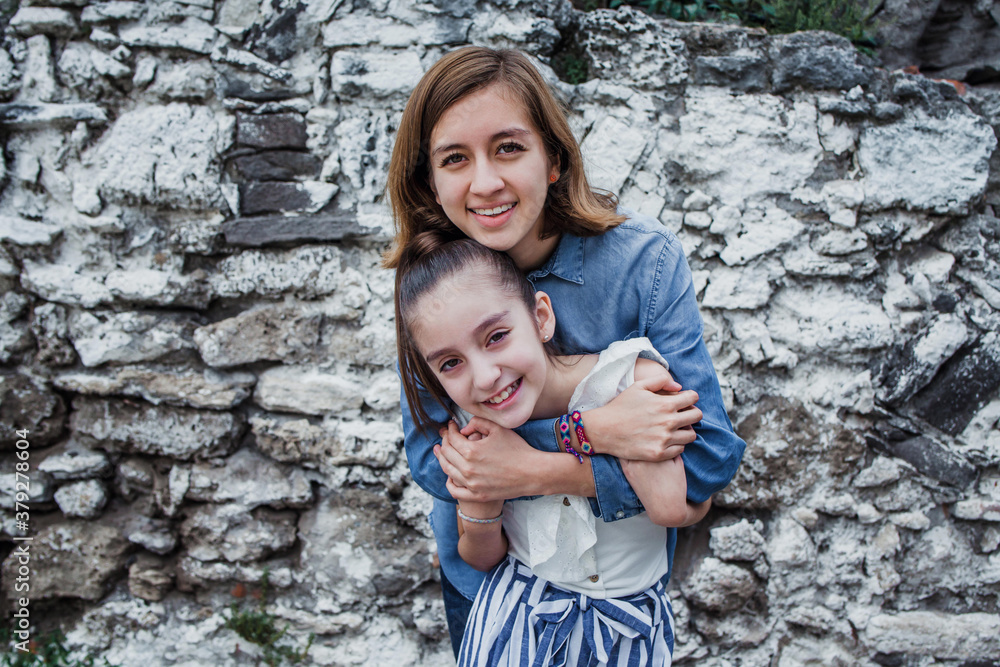 Portrait of two cheerful hispanic sisters hugging and looking at camera in Latin America Portrait of two cheerful hispanic sisters hugging and looking at camera in Latin America