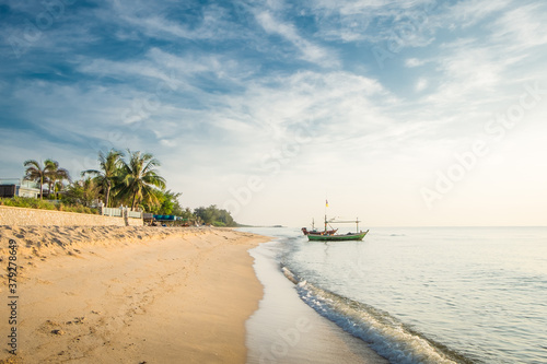 Beautiful view of the turquoise waves with the blue sky and white clouds and fisherman s boat on sandy beach on vacation in Hua Hin  Prachuap Khiri Khan Province  Thailand.