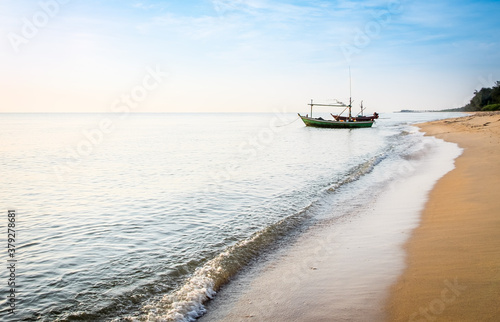 Beautiful blue sea wave and fishing boat on sand beach for vacations in Hua Hin, Prachuap Khiri Khan Province, Thailand.