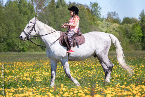 Little girl rides a white horse at sunny day, close-up © evannovostro