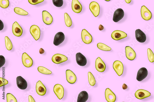 Avocado. Background made from isolated Avocado pieces on pink background. Flat lay of fresh ripe avocados and avacado pieces.
