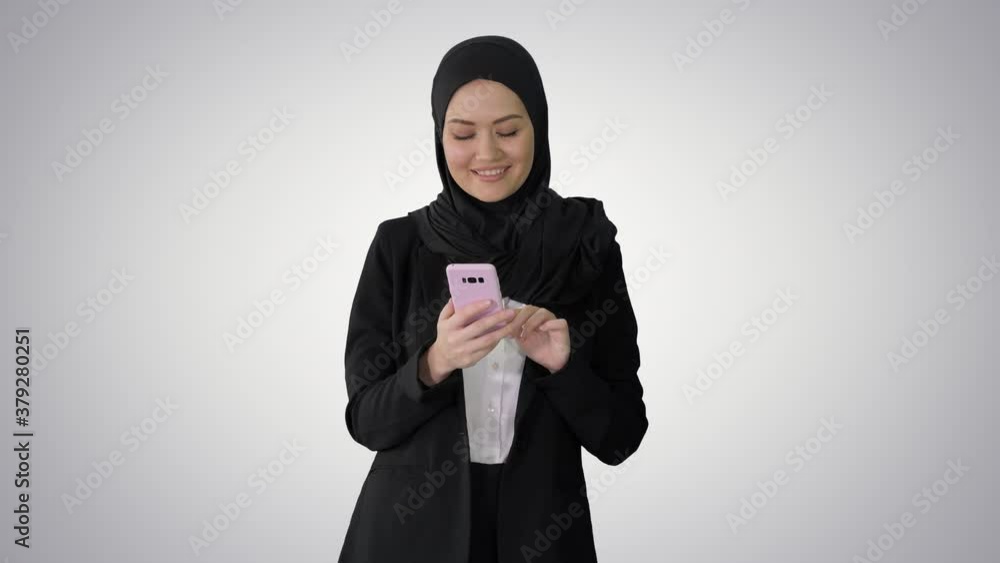 Smiling arab woman using smart phone on gradient background. Smiling arab woman using smart phone on gradient background.