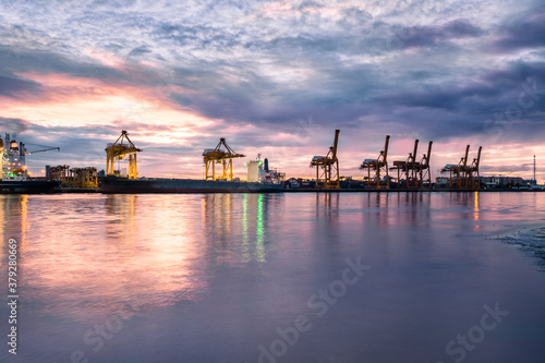 Harbor with anchored ship. Container cargo freight ship with working crane bridge at a shipyard in for logistic transportation import and export at Asia haven port background, Samutprakarn, Thailand. © Chaiyaphruek