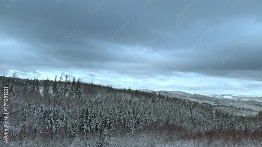 Aerial view over a man standing on a hill, looking on mountains and snowy, polar forest, on a dark, cloudy, winter day - rising, drone shot Aerial view over a man standing on a hill, looking on mountains and snowy, polar forest, on a dark, cloudy, winter day - rising, drone shot