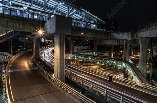 Overpass of the light trails with Bangkok city background at night. Beautiful curves. Selective focus. © num
