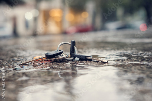 Schilderij op canvas Set of lost keys on the ring on wet ground in the street