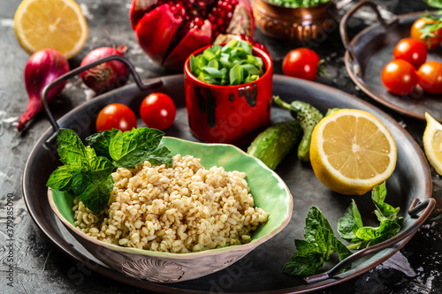 Top view of Middle eastern or arab dishes and assorted meze and snacks tabbouleh vegetable salad, olives, tomatoes, pomegranate, herbs. Traditional oriental salad Tabouleh