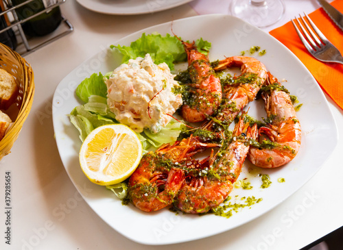 Close up of tasty king shrimps, served with lettuce and salad from potatoes