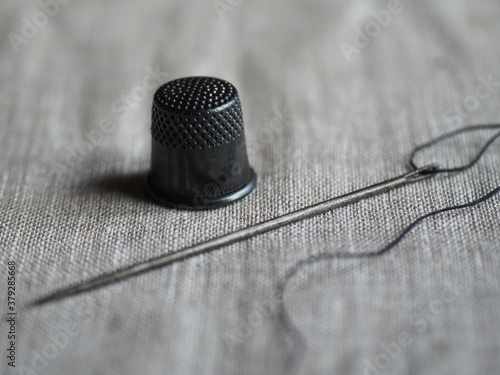 Sewing accessories - needle, thimble on a gray background.