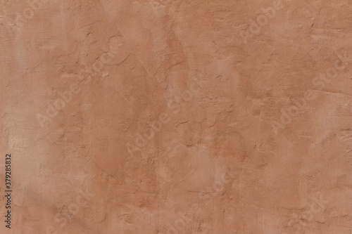 Abstract background of an exterior reddish brown adobe style textured wall surface