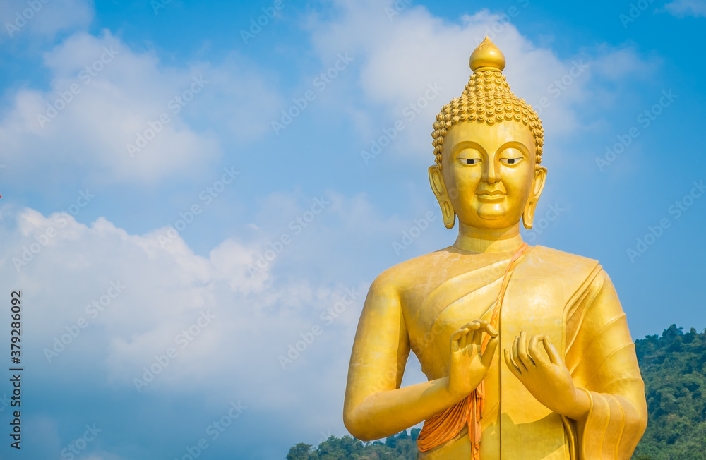 Beautiful golden buddha statue on blue sky background at Makha Bucha Buddhist memorial park, Nakhon Nayok Province, Thailand. Copy space Beautiful golden buddha statue on blue sky background at Makha Bucha Buddhist memorial park, Nakhon Nayok Province, Thailand. Copy space
