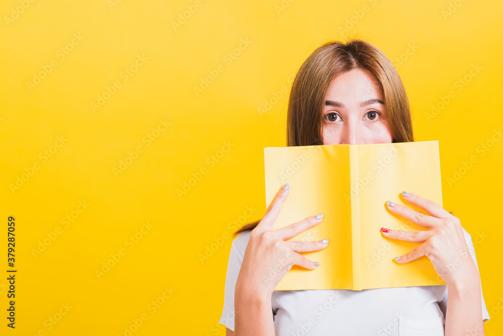 Portrait Asian Thai beautiful happy young lifestyle woman stands holding yellow book or diary her looking to camera, studio shot isolated on yellow background, with copy space Portrait Asian Thai beautiful happy young lifestyle woman stands holding yellow book or diary her looking to camera, studio shot isolated on yellow background, with copy space