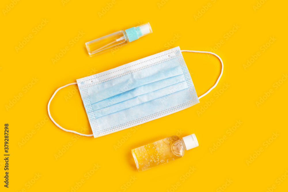 Face masks and hand sanitizer bottles on yellow background. Face masks and hand sanitizer bottles on yellow background.