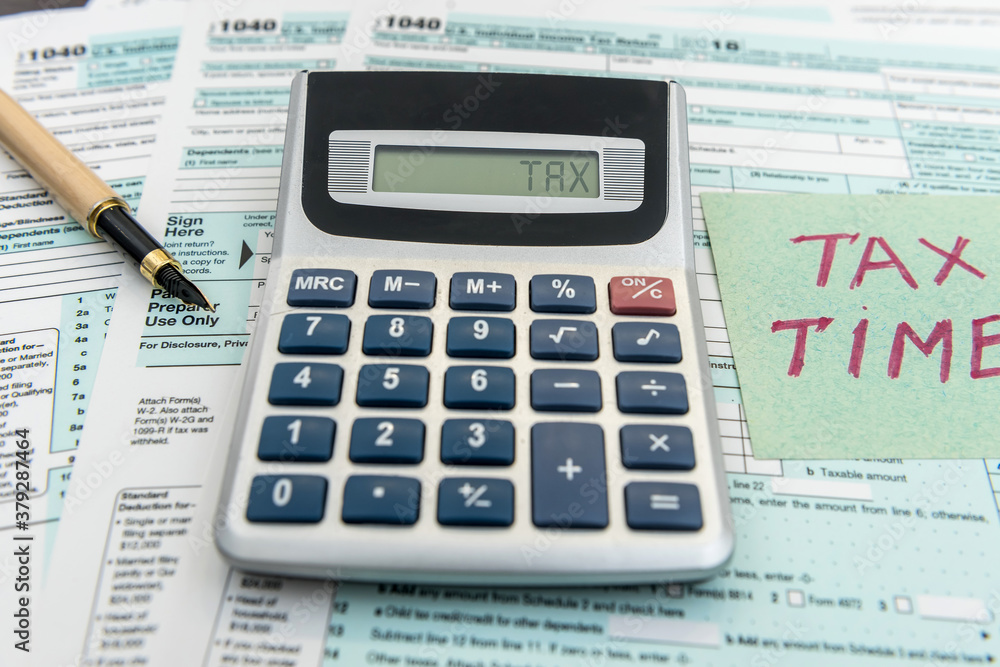 Tax financial forms with pen and calculator and sticker with text Tax Time Tax financial forms with pen and calculator and sticker with text Tax Time