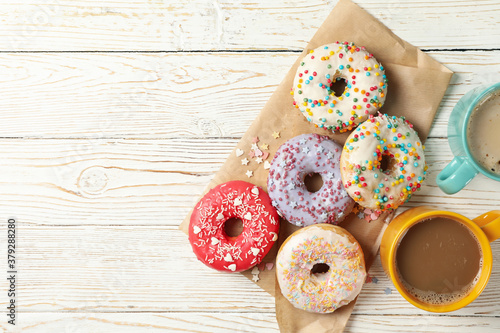 Coffee and tasty donuts on wooden background, top view