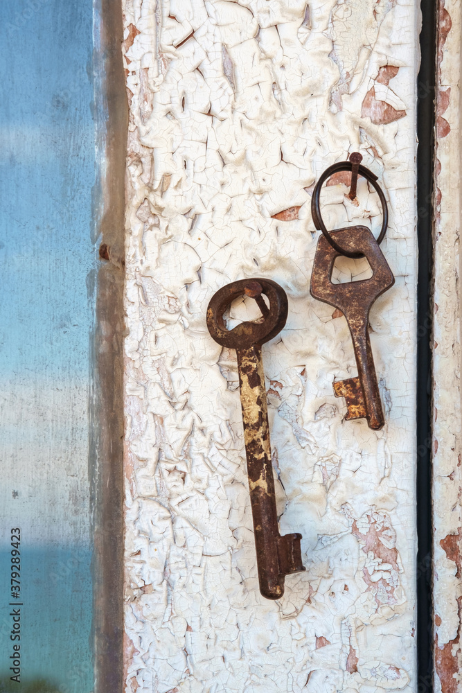 Old rusty keys on a wooden door frame with broken white paint