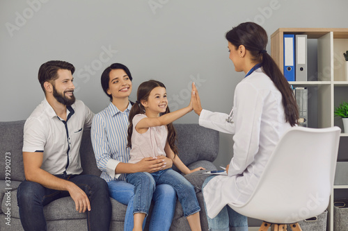 Smiling girl giving high five to woman doctor during successful consultation in clinic