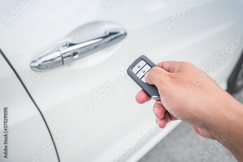 Businessman opens his luxurious car door with a modern remote control key. The young man is locking the automobile with the security system. Keyless in male hand.