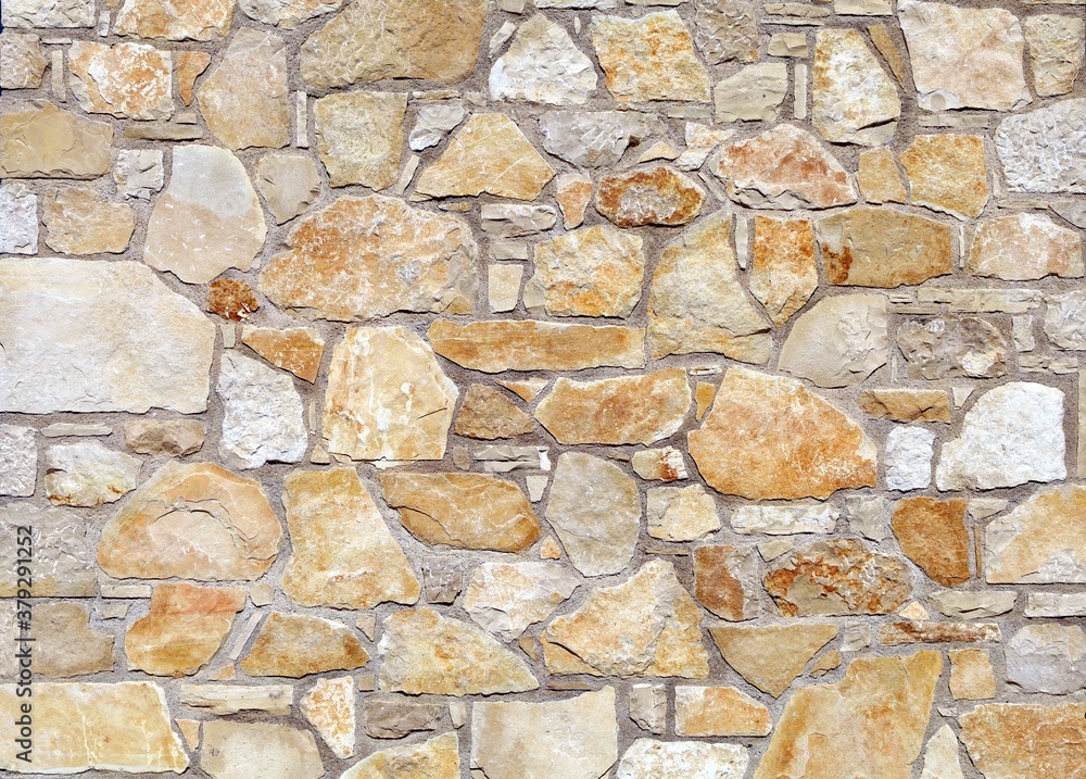 White and orange stone wall made of large flat natural rocks. Background and texture.