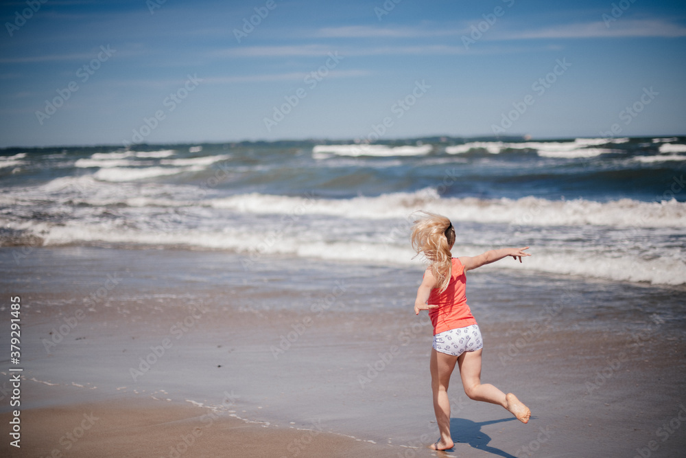 happy child running and jumping in the waves at beach. Reuniting with nature.