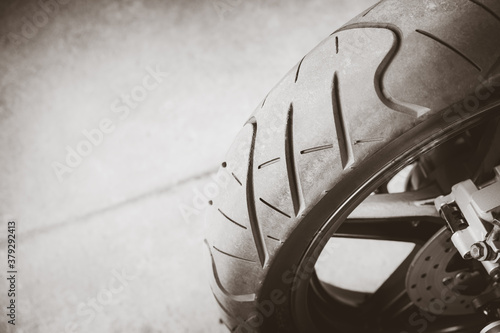 Rear view of motorcycle tire on the road with copy space. Close up classic motorbike tyre tread wheel on the asphalt roadway. Monochrome or Black and White style.