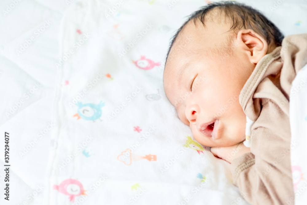 Cute Asian newborn baby boy lying fast sleeping on the bed in a bright room. Child resting in the bedroom at home. Breastfeeding or early childhood development concept. Copy space Cute Asian newborn baby boy lying fast sleeping on the bed in a bright room. Child resting in the bedroom at home. Breastfeeding or early childhood development concept. Copy space