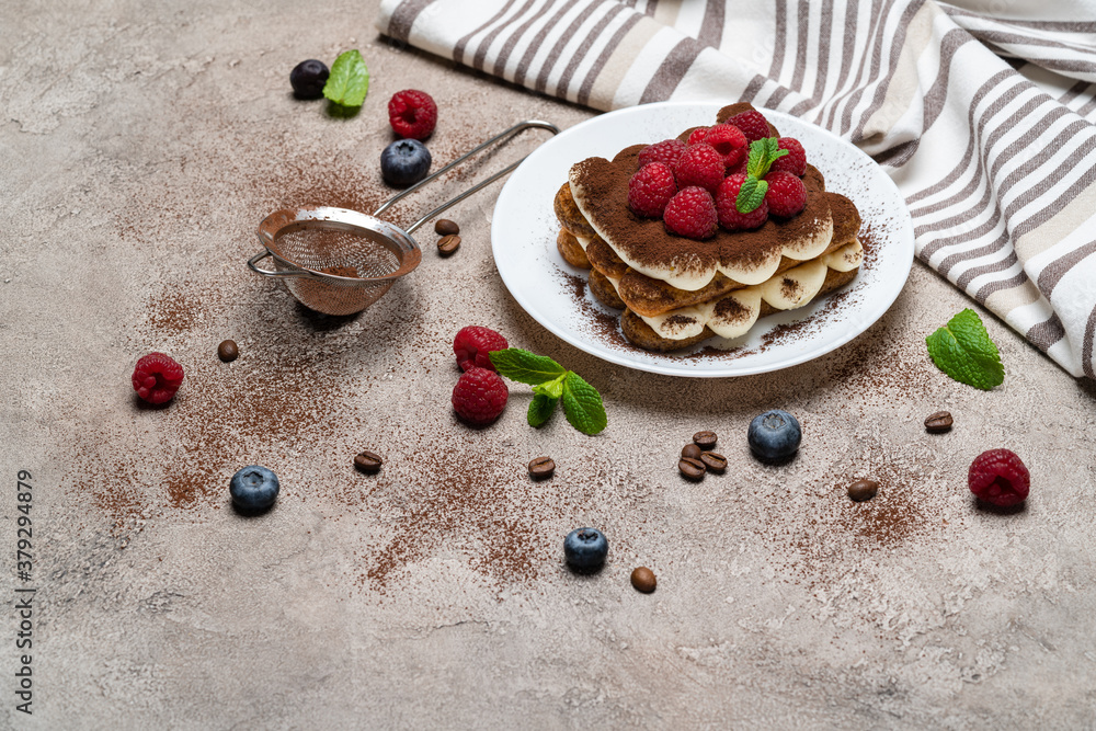 portion of Classic tiramisu dessert with raspberries on grey concrete background portion of Classic tiramisu dessert with raspberries on grey concrete background