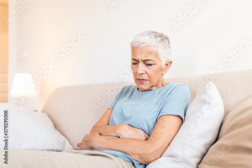 Canvas Print Old age, health problem and people concept - senior woman suffering from stomach ache at home