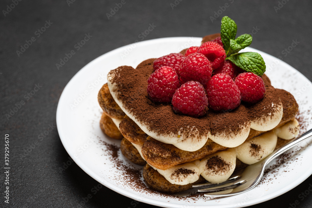 portion of Classic tiramisu dessert with raspberries on dark concrete background portion of Classic tiramisu dessert with raspberries on dark concrete background