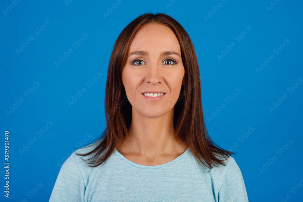 Portrait of a smiling brunette in a blue t-shirt looking at the camera, isolated on a blue background. Portrait of a smiling brunette in a blue t-shirt looking at the camera, isolated on a blue background.