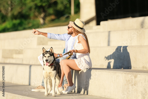 Young couple with cute Husky dog outdoors