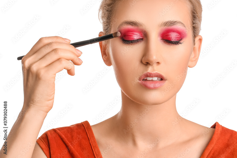 Young woman applying beautiful eyeshadows against white background