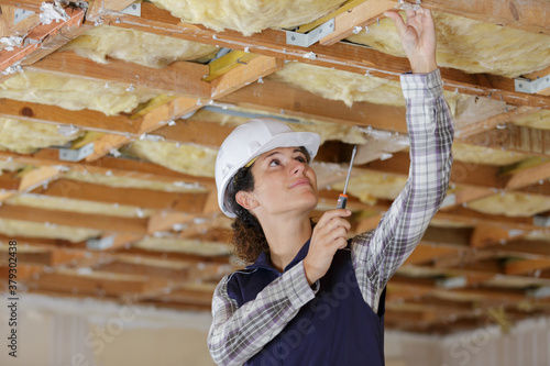 Εκτύπωση καμβά young female builder working on ceiling joist