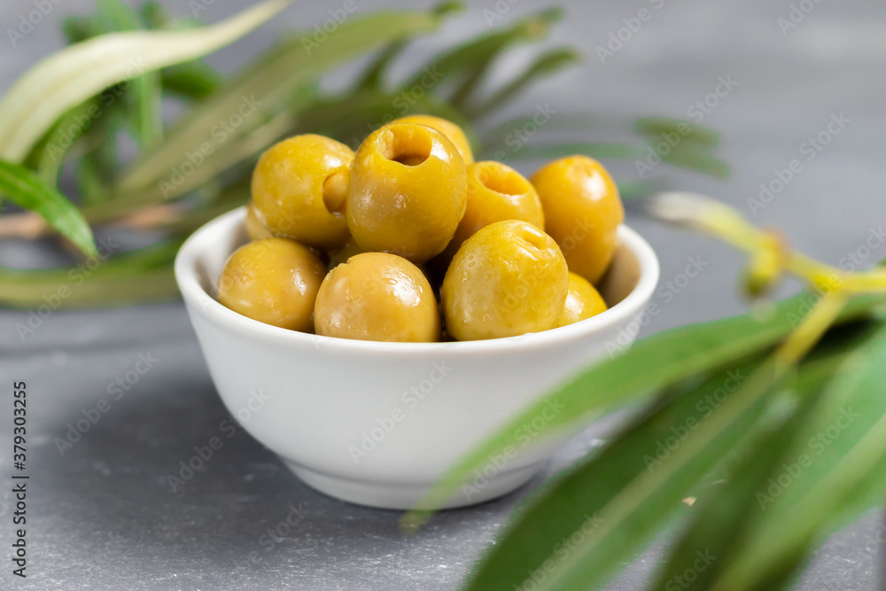 Pitted green olives in white plate with green leaves Pitted green olives in white plate with green leaves