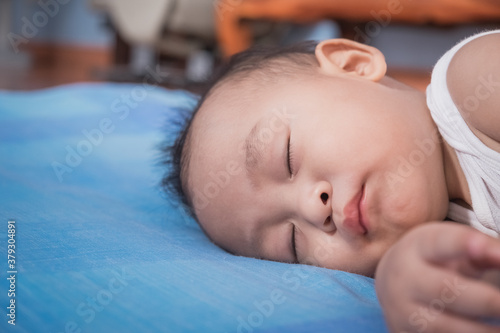 Shot of little asian baby boy sleeping on sofa at home. Breastfeeding or early childhood development concept