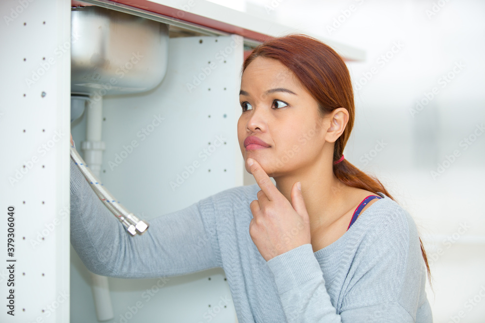 woman inspecting under the sink woman inspecting under the sink