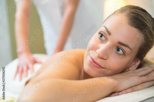 smiling young woman having neck massage in spa