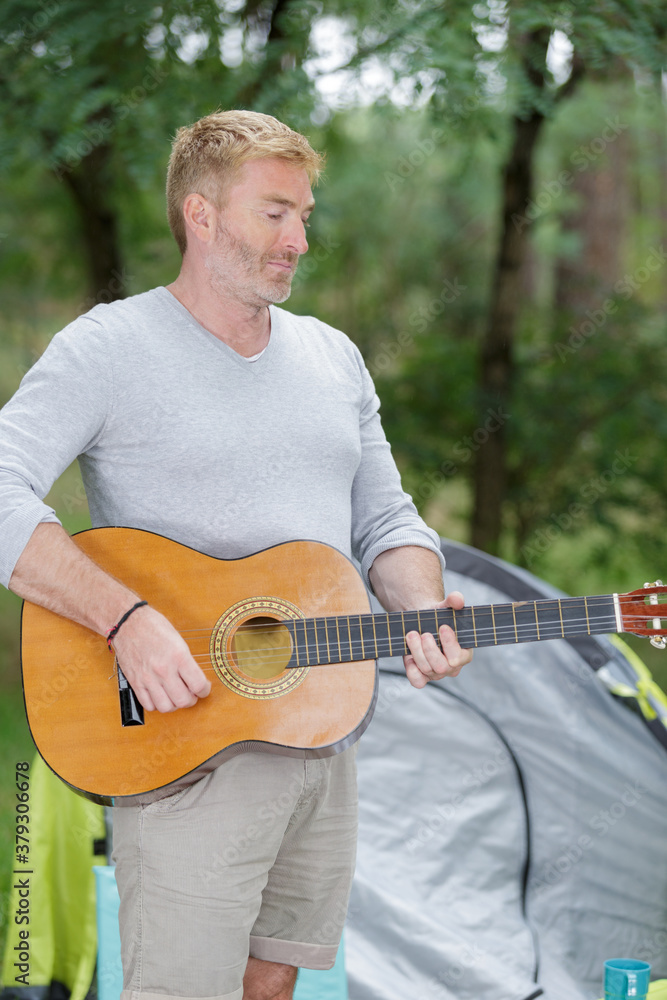 Obraz premium man playing guitar outside his tent