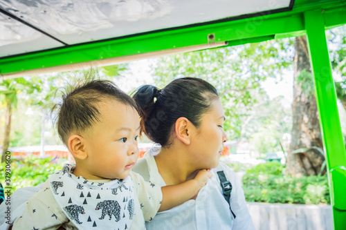 Shot of Mother and her little son sit on tram in summer day at the zoo. Concept of friendly family and vacation