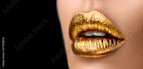 Golden lipstick closeup. Metal gold lips. Beautiful makeup. Sexy lips, bright paint on beautiful model girl's mouth, close-up. Metallic Lipstick closeup. Isolated on black background