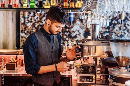 Close-up of barista making espresso from a coffee machine in a restaurant  bar or pub. Professional coffee brewing. Latte art with espresso machine steam in cafe. Vintage color tone