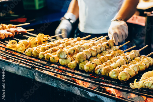 Closeup of grill squid on stick for sale. Thai street food vendor in Bangkok, Thailand.